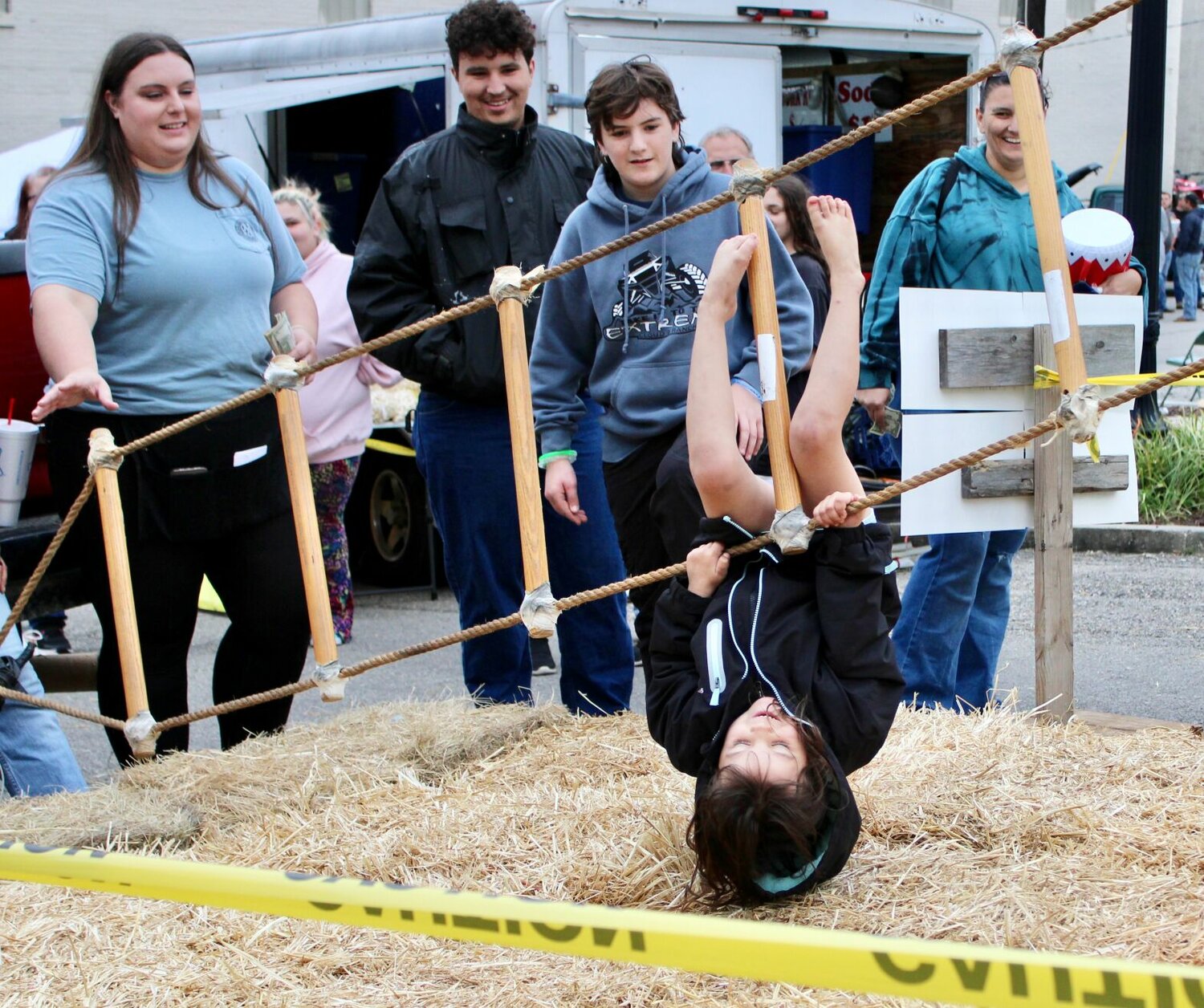 Despite falling temperatures and windy conditions, there was a great turnout at the Thayer Chamber of Commerce Fall Festival held Saturday in downtown Thayer. There were plenty of games of skill for the younger set, many of them fundraisers for local youth and religious organizations. Here, a girl takes a turn at trying to climb a rope ladder to reach a $20 bill taped to the top, but gets topsy-turvy before reaching her goal and landing upside down on the straw laid down below.